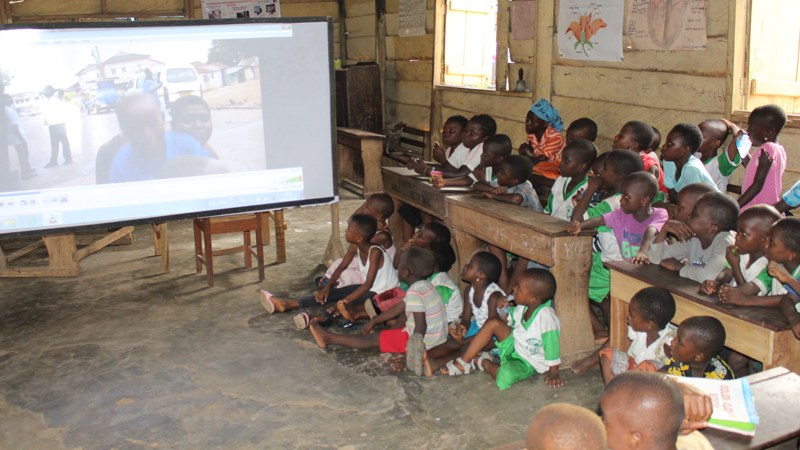 Schulkinder in Ghana schauen auf eine Leinwand